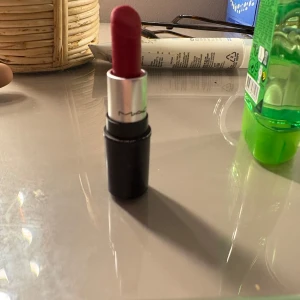 Rött läppstift och läppglans från MAC - Säljer ett snyggt rött läppstift och ett matchande läppglans från MAC. Läppstiftet har en klassisk svart hylsa med silverdetaljer, medan läppglanset kommer i en genomskinlig tub med svart lock. Perfekt för att ge en djärv färg till dina läppar!