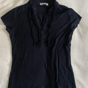 Svart kortärmad topp från Dolce & Gabbana - Snygg svart kortärmad topp från Dolce & Gabbana med volangdetaljer. Storlek L men passar som en S.