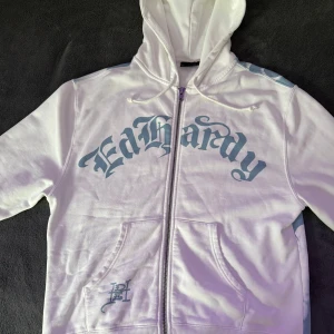  Ed Hardy x Urban Outfitters Hoodie - Säljer en riktigt snygg vit hoodie från Ed Hardy x Urban Outfitters pga att jag inte använder den någon mer. Har använd den max 2 gånger (hemma) så skicket på den e 10/10. Priset kan diskuteras vid snabb affär.