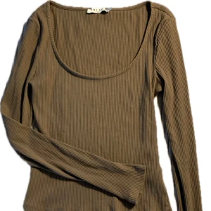 Brun ribbad långärmad topp från NA-KD - Snygg brun ribbad topp från NA-KD med långa ärmar och rund urringad halsringning. Perfekt för stilren outfit, även super skön på!