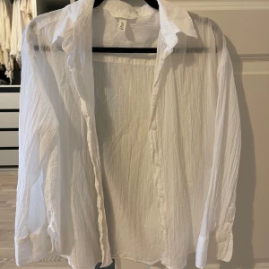 Vit blus från H&M - Säljer en stilren vit blus från H&M i storlek L. Blusen har en luftig design med långa ärmar och knappar framtill. Perfekt för en avslappnad och chic look.