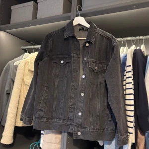 Svart jeansjacka från Missguided - Snygg svart jeansjacka från Missguided i storlek XS. Jackan har klassisk design med knappar framtill och två bröstfickor med lock. Perfekt för en cool och avslappnad stil.