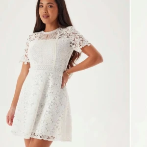 Vit spetsklänning - Säljer en elegant vit spetsklänning med korta ärmar och ett vackert blommönster. Klänningen har en rund hals och en figursydd passform som ger en feminin siluett. Perfekt för sommarens alla tillfällen. Använd en dag, som ny!🥰