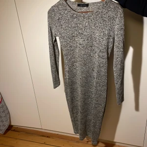 Grå tight  klänning från Amisu - Snygg grå klänning från Amisu i en mjuk och bekväm stickad kvalitet. Den har en figurnära passform och långa ärmar, perfekt för kyligare dagar. Klänningen är enkel och stilren, vilket gör den lätt att matcha med olika accessoarer. Klänningen är köpt second hand men aldrig använd. 