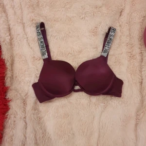 Lila aktig bh från Victoria's Secret - Säljer en snygg lila färgad bh från Victoria's Secret med push up och axelband med textdetaljer. Helt som ny använd 2 gånger, den här modellen säljs inte längre dom har bytt ut så texten inte finns på deras nya så passa på om ni gillar den gamla modellen!🥰