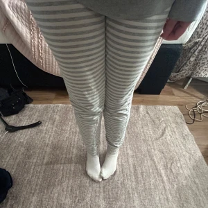 Randiga mjukisbyxor i grått och vitt - Mysiga och bekväma mjukisbyxor med grå och vita ränder. Perfekta för en avslappnad dag hemma. Byxorna har en tight passform och är tillverkade i ett mjukt material.