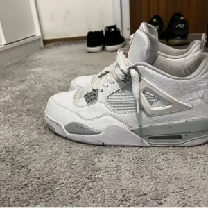 Jordan 4 Oreo  - Jordan 4  med grå detaljer och snörning. Skorna har en klassisk design med det ikoniska Jumpman-logotypen på hälen. Perfekta för dig som älskar stilrena sneakers med en sportig touch.