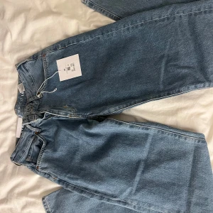 Blå jeans med rak passform - Säljer ett par klassiska blå jeans med rak passform. De har en låg midja och är i storlek W27 L32. Perfekta för en avslappnad stil. Helt nya!