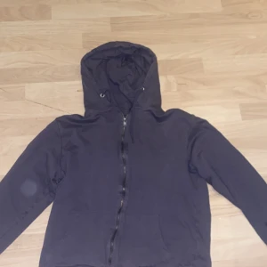 Svart hoodie med dragkedja - Säljer en svart hoodie från lager 157 med dragkedja och huva. Perfekt för en avslappnad stil. Den har långa ärmar och en bekväm passform.