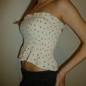 Vit tub topp - Söt vit axelbandslös topp med små röda hjärtan och volangdetalj i nederkant. ❣️🤍❣️