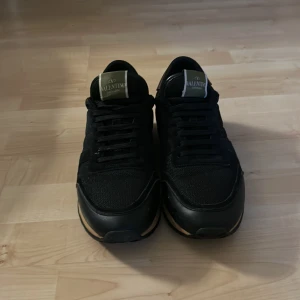 Svarta valentino rockrunners  - Snygga svarta sneakers från Valentino med en stilren design. Skorna har en svart ovandel med snörning och en kontrasterande sula i beige. Perfekta för en trendig look.