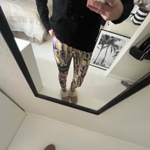 Färgglada leggings från Stronger - Säljer ett par färgglada leggings från Stronger i storlek XS. De har ett unikt mönster med bokstäver i olika färger som rosa, blå och gul. Perfekta för att liva upp träningsgarderoben! 💞