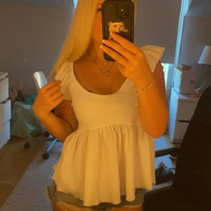 Vit blus med volangärmar - Säljer en söt vit blus med volangärmar. Blusen har en luftig passform och är perfekt för varma dagar. Den är tillverkad i ett lätt och bekvämt material. Använt ett fåtal gånger .