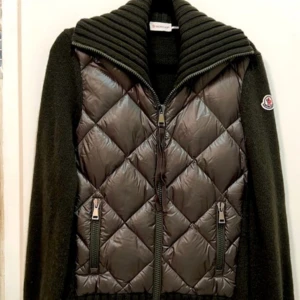 Grön cardigan quiltad jacka från Moncler - Lägg bud! Vill se vad jag kan få för jackan! Grön cardigan svart quiltad jacka från Moncler med dragkedja och ribbad krage. Scan inuti som funkar, chip i loggan som kopplas till hemsidan och även kvitto tillkommer!  Jackan har långa ärmar och två praktiska fickor med dragkedjor. Perfekt för kyligare dagar.