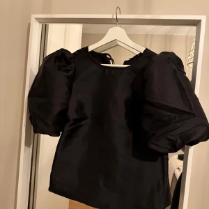 Svart blus med puffärmar - Elegant svart blus med stora puffärmar och rund halsringning. Perfekt för en stilren look med en touch av dramatik. Passar bra till både kjol och byxor. Helt oanvänd nypris 599:-