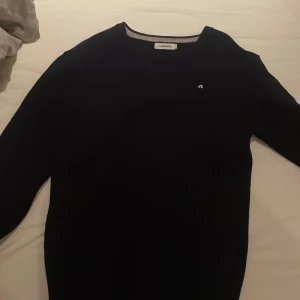 Svart tröja från J.Lindeberg - Snygg svart tröja från J.Lindeberg med diskret logga på bröstet. Perfekt för en stilren look. Tröjan har långa ärmar och en klassisk passform.  helt ny.🌟🌟