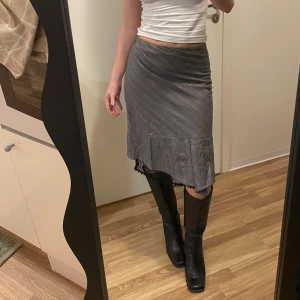 Vintage Grå randig kjol från Marc Cain - Snygg grå kjol från Marc Cain med subtila ränder och volangdetalj i nederkant. Litet märke/hål som ni ser på bilden men syns inte alls vid användning. Ingen storlek i men jag är 160cm och bär XS