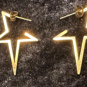 Guldpläterade stjärnörhängen - Snygga örhängen i form av stjärnor i guld. Cirka 4 cm långa och 3 cm breda. Gyllene stoppar Perfekta för att ge en glittrig touch till din outfit. De har en modern och stilren design som passar till många tillfällen. Mint condition. 