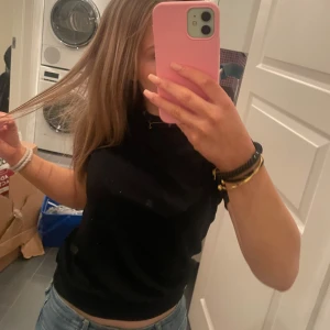 Svart glittrig topp - Säljer en svart glittrig topp med korta ärmar. Toppen har en tight passform och är perfekt för en kväll ute. Materialet är mjukt och bekvämt.💗