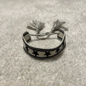 Flätat Armband  - Snyggt svartvitt armband med stjärnmönster och justerbara tofsar för perfekt passform. Liknar de eftertraktade Dior armbanden. Vid minsta fråga eller fundering hör av er🤝