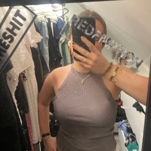 Grå/rosa ribbad linnetopp från Zara - Säljer en stilren grå ribbad linnetopp från Zara. Toppen har en tight passform och är ärmlös, perfekt för en avslappnad look. Den är tillverkad i ett mjukt material som känns skönt mot huden.