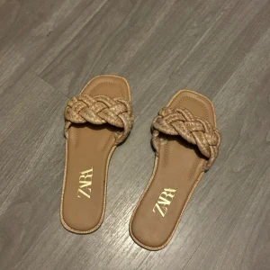 Beige sandaler från Zara - Snygga beige sandaler från Zara med flätad detalj över foten. Perfekta för sommardagar och enkla att matcha med olika outfits. Storlek 37 men lite trånga vid snörningen.