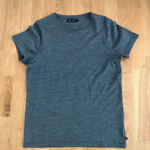 Grå t-shirt från Riley - Säljer en stilren grå t-shirt från Riley i storlek M. Perfekt för en avslappnad look med sin mjuka bomullskänsla och klassiska design. Kortärmad och lätt att matcha med olika outfits.