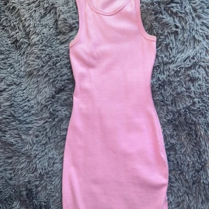 Rosa ärmlös klänning - Säljer en superfin rosa klänning i ett mjukt och stretchigt material. Den är ärmlös och har en tight passform som framhäver figuren. Perfekt för sommardagar eller en avslappnad fest. Klänningen är i mycket bra skick och redo för nya äventyr!