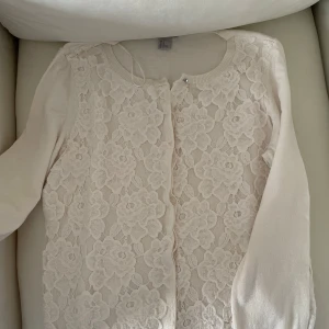 Vit spetskofta från H&M - Säljer en superfin vit kofta från H&M i storlek M. Den har vackra spetsdetaljer framtill som ger en romantisk touch. Perfekt för både vardag och fest! Koftan är långärmad och i mycket bra skick. Passar perfekt till vår och sommar.