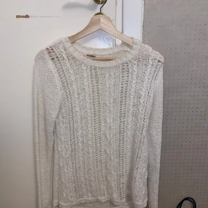 Vit stickad tröja från H&M - Säljer en vit stickad tröja från Rosebud med ett fint spetsmönster. Tröjan har långa ärmar och en rund halsringning. Använd ett fåtal gånger.