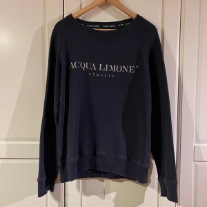 Mörkblå tröja från Acqua Limone - Snygg mörkblå tröja från Acqua Limone med tryck på både fram- och baksidan. Tröjan har långa ärmar och ribbade muddar vid ärmslut och nederkant. Perfekt för en avslappnad stil.
