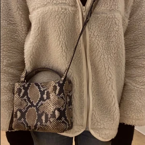 Ormmönstrad axelväska - Snygg axelväska med ormmönster i svart och beige. Väskan är köpt ifrån arket för 1200kr 
