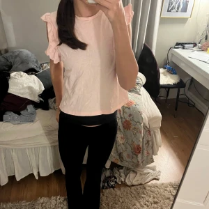 Ljusrosa topp med volangärmar - Söt ljusrosa topp med volangdetaljer på ärmarna. Perfekt för en avslappnad och stilren look. Passar bra till både jeans och kjol.