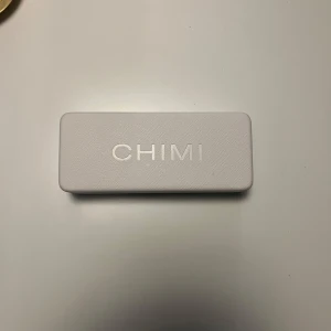 Svart/grå solglasögon från Chimi - Snygga svarta solglasögon från Chimi med en stilren design. De har en fyrkantig form och kommer i ett elegant fodral. Perfekta för att ge din outfit en cool touch.