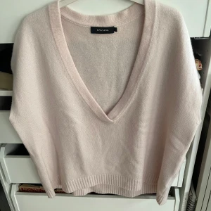 Ljusrosa kashmirtröja/väst från Lisa Yang - Säljer en supermjuk och lyxig ljusrosa kashmirtröja från Lisa Yang. Den har en snygg v-ringning och ribbade kanter som ger en stilren look. Perfekt för både vardag och festliga tillfällen. Tröjan är i mycket bra skick och känns som en dröm att ha på sig! Ljusrosa 