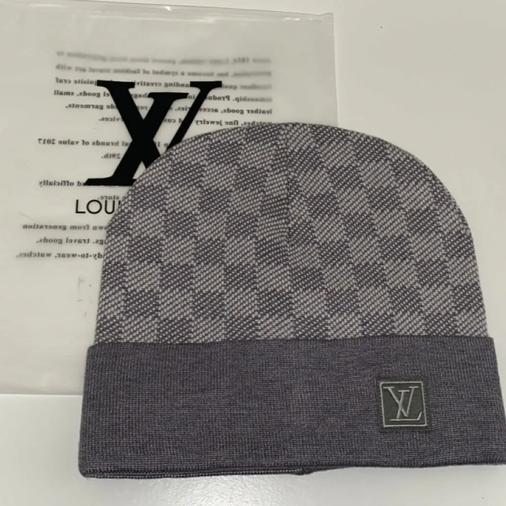 Snygg grå rutig mössa från Louis Vuitton i ett mjukt och bekvämt material. Den har en klassisk design med ett diskret LV-märke framtill. Perfekt för att hålla sig varm med stil under kyliga dagar.. Accessoarer.