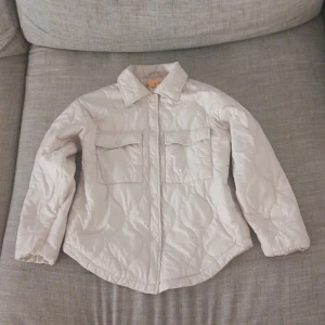 Beige quiltad jacka från Gina Tricot - Säljer en superfin beige quiltad jacka från Gina Tricot i storlek 146/152. Jackan har långa ärmar och knappar framtill. Perfekt för höst och vår med sin stilrena design och bekväma passform. Passar både till vardags och lite finare tillfällen. 🧥✨