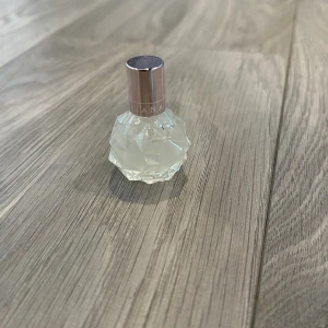 Parfymflaska  - Elegant parfymflaska med en facetterad, kristalliknande design. Flaskan har en genomskinlig bas och ett roséguldfärgat lock. Perfekt för att ge en lyxig känsla till din parfymkollektion.