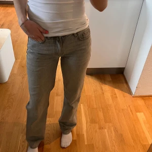 Grå lågmidjade jeans - Snygga grå jeansbyxor med en klassisk straight passform. De har en lågmidjade design och är perfekta för en avslappnad stil. Byxorna har traditionella fem fickor och en dragkedja framtill. Storlek 34 mycket bra skick!
