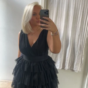 Svart volangklänning - Elegant svart balklänning med volanger och djup v-ringning. Den är endast en gång jag har vanligtvis M/L klänningen är i storlek 42. Nypris 1799