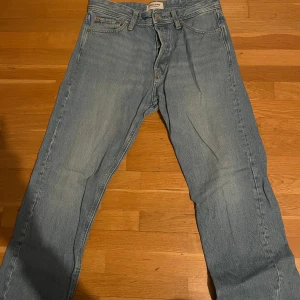 Blå Jack & Jones jeans Relaxed Chris - Säljer ett par blå jeans i modellen Relaxed Chris. De har en avslappnad passform och är perfekta för en casual look. Jeansen är i bra skick och har en klassisk design med fem fickor och knappgylf. Perfekta för vardagsbruk!
