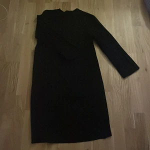 Svart stickad klänning - Säljer en mysig svart stickad klänning i mycket bra skick. Den har en enkel och stilren design med långa ärmar och ribbade detaljer. Perfekt för höst och vinter, både till vardags och festligare tillfällen. Passar bra med ett par snygga stövlar eller sneakers.