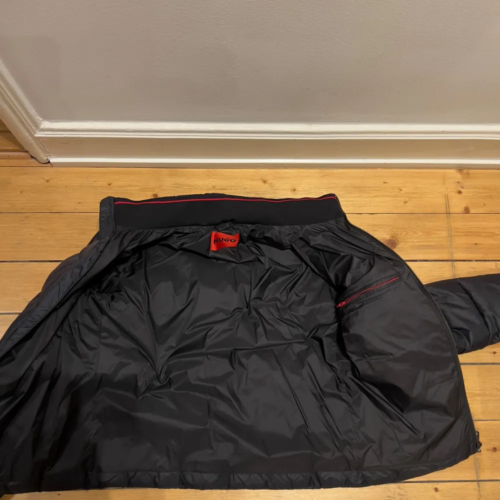 Säljer en svart pufferjacka från Hugo Boss i mycket bra skick. Jackan har en dragkedja framtill och är quiltad för extra värme. Perfekt för höst och vinter! Den har en normal passform och är långärmad. Superbekväm och stilren design.. Takit.