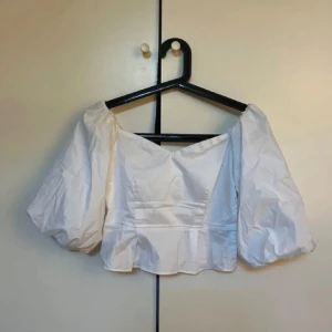 Vit offshoulder blus - Säljer en superfin vit offshoulder blus med puffiga ärmar. Den är perfekt för sommaren och har en söt, croppad stil som passar både till vardags och fest. Materialet känns lätt och luftigt, vilket gör den bekväm att bära hela dagen.