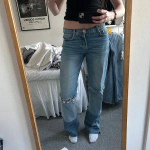 Blå bootcut jeans - Säljer ett par blå bootcut jeans med slitna detaljer vid ena knäna. Jag e 173