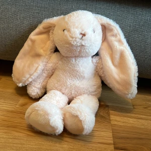 Mjuk kanin från Teddykompaniet - Söt och mjuk kanin från Teddykompaniet i en ljusrosa färg. Den har långa öron och är perfekt som gosedjur. Kaninen är tillverkad i ett mjukt och kramvänligt material, vilket gör den till en favorit hos barn.