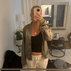 Grön bomberjacka från Pieces - Snygg grön bomberjacka från Pieces. Jackan har en klassisk bomberstil med dragkedja framtill och långa ärmar. Perfekt för en cool och avslappnad look. Ganska tunn.