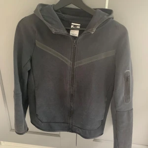 Svart Nike tech fleece - Tjena! Säljer nu min gamla Nike tech då den är för liten och inte min stil. Den passar om du är 155 till 162cm då det är storlek L i barn. Skicket är 8/10. Nypris är 1100kr och mitt pris är 550. hör av er om ni ha några frågor köparen står för frakt 