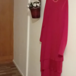 Röd klänning från Schneberger - Snygg röd klänning från Schneberger i ett mjukt och bekvämt material. Den har långa ärmar och en elegant, flytande design som passar perfekt för både vardag och fest. Klänningen är i mycket bra skick och redo att ge din garderob en färgklick!⁷