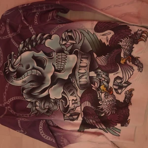 Långärmad tröja med dödskalle och örnar - Cool långärmad tröja med ett stort tryck av en dödskalle och örnar. Färgerna går i lila och rosa med kedjemönster och detaljer i guld. Perfekt för en unik och edgy stil. Passar bra till höst och vår.